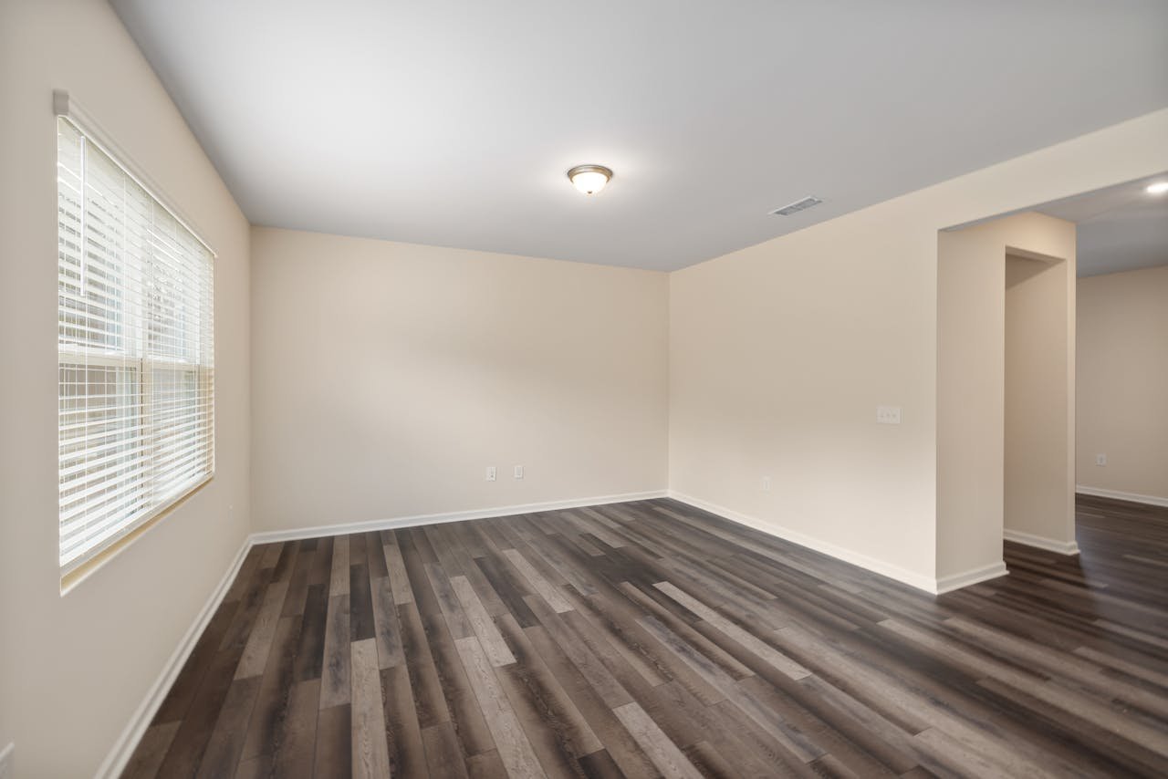 A bright, empty room featuring dark wooden flooring and white walls, ideal for interior design projects.