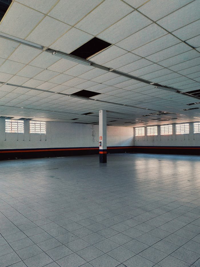 Empty industrial space with tiled flooring and grid-pattern ceiling.