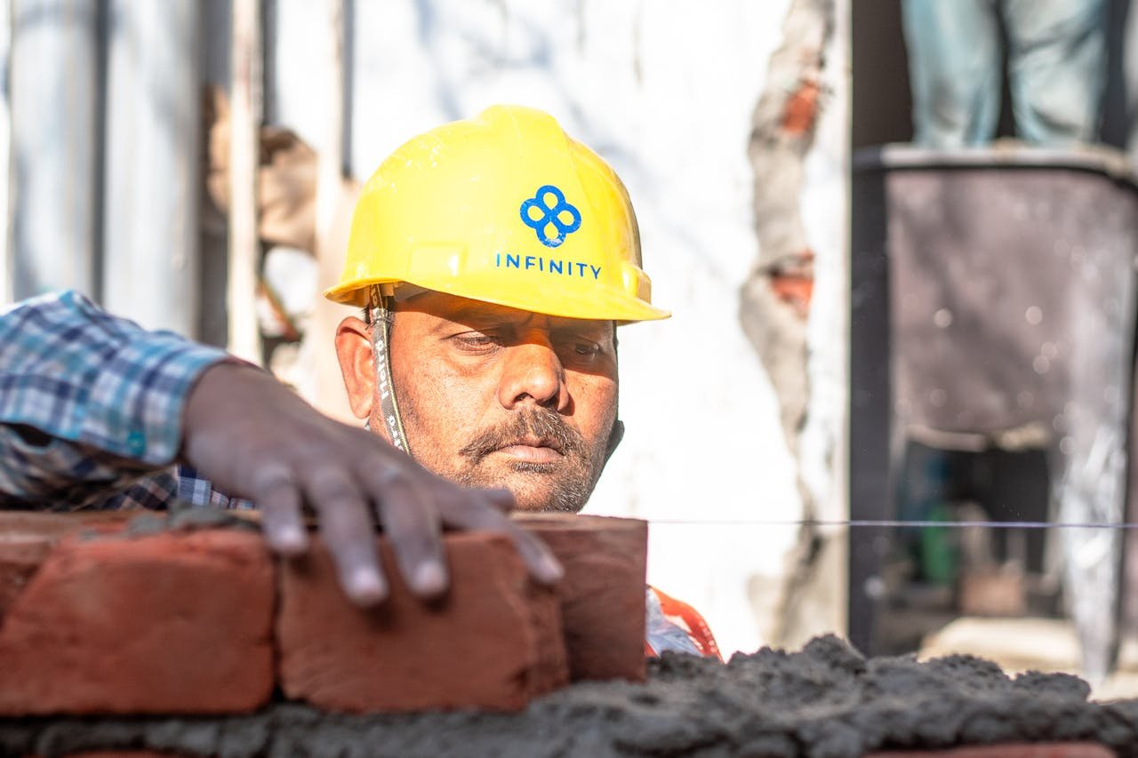 A construction worker carefully aligning bricks on a wall in Delhi, India.